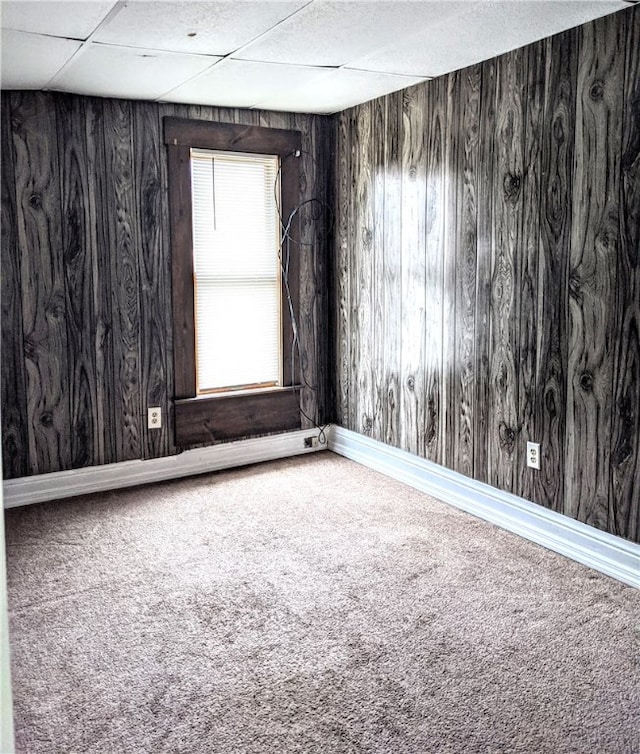 carpeted empty room featuring wooden walls