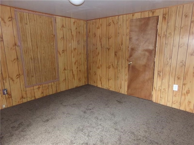 carpeted spare room featuring wooden walls