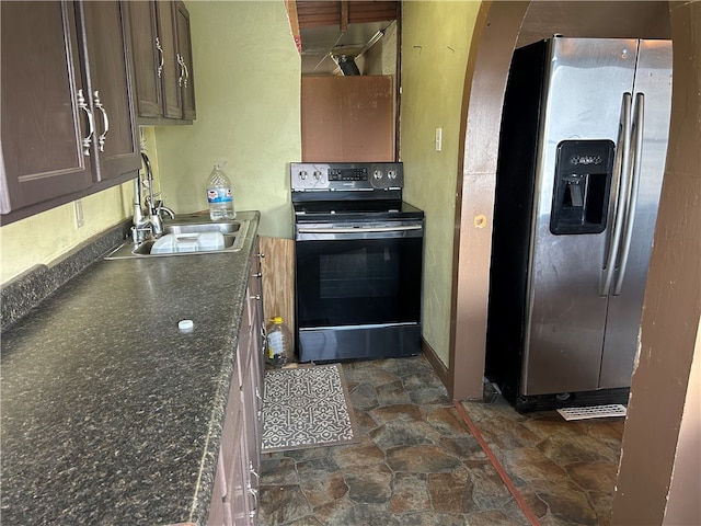 kitchen featuring dark stone counters, stainless steel fridge with ice dispenser, black electric range oven, and sink