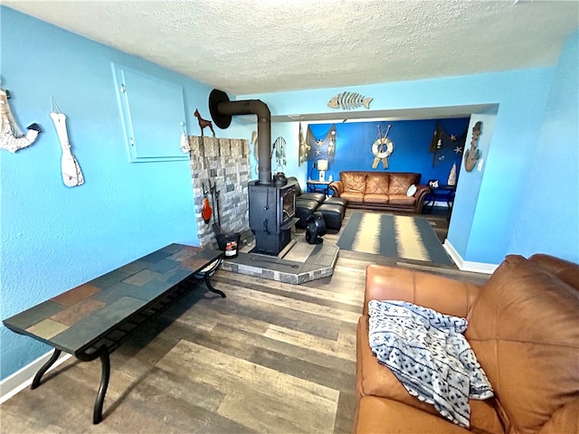 workout area featuring a wood stove, hardwood / wood-style floors, and a textured ceiling