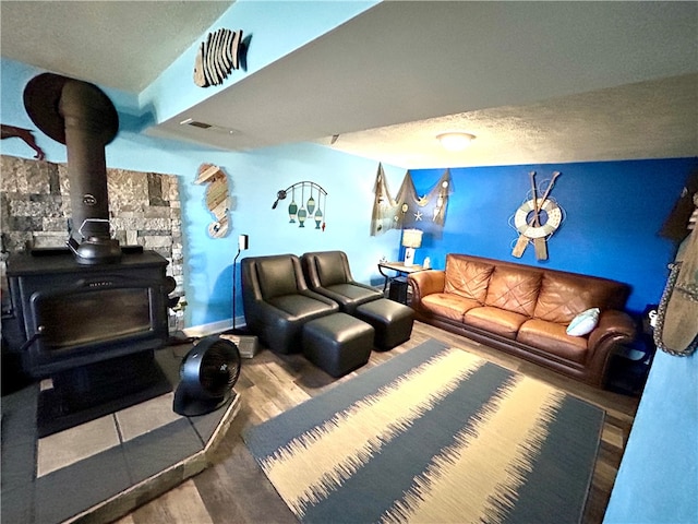 living room with a wood stove, wood-type flooring, and a textured ceiling