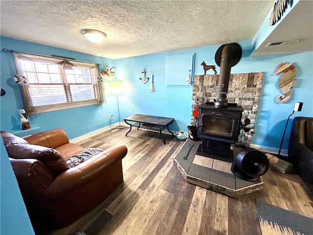 living room featuring hardwood / wood-style flooring, a textured ceiling, and a wood stove