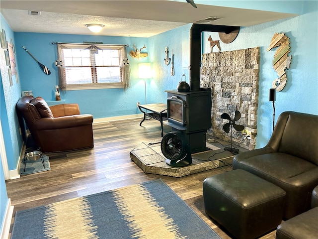 sitting room featuring hardwood / wood-style floors, a wood stove, and a textured ceiling