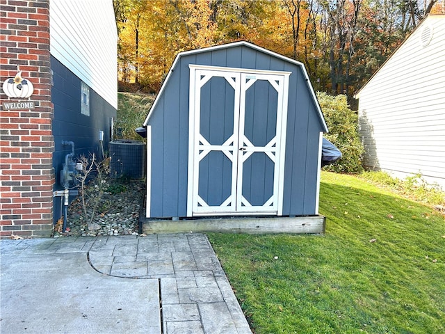 view of outdoor structure featuring central air condition unit and a lawn