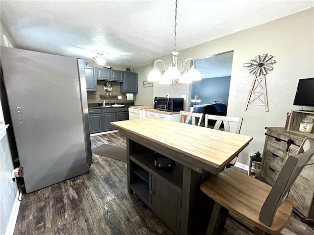 dining room with dark hardwood / wood-style flooring, sink, a notable chandelier, and a textured ceiling