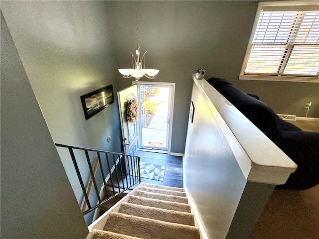 stairway featuring a healthy amount of sunlight and an inviting chandelier