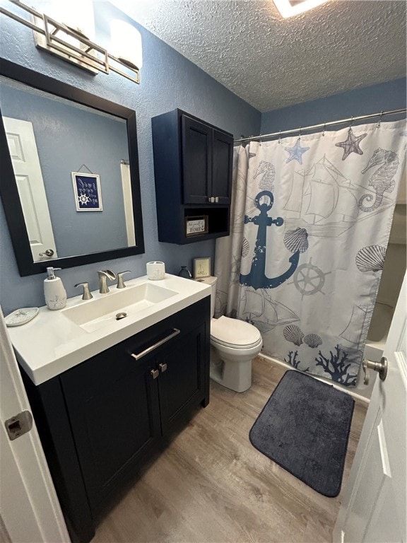 bathroom featuring a textured ceiling, curtained shower, wood-type flooring, vanity, and toilet