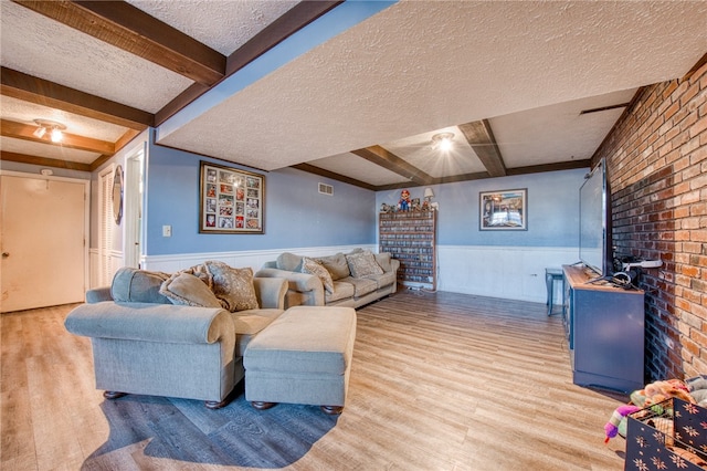 living room with light wood-type flooring, a textured ceiling, and beam ceiling