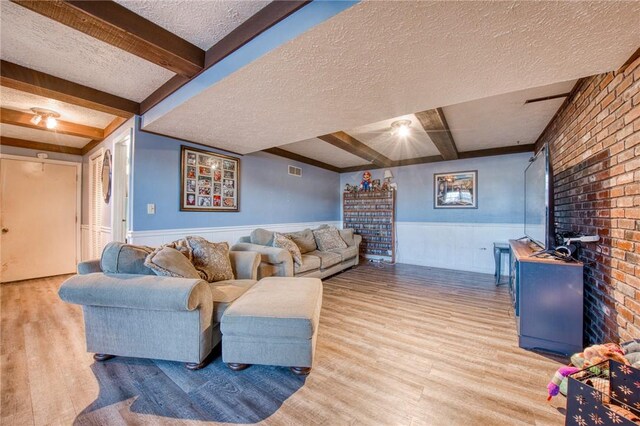 2759 Brodhead Rd, Aliquippa, PA 15001 - living room with a textured ceiling, a wainscoted wall, wood finished floors, beam ceiling, and brick wall
