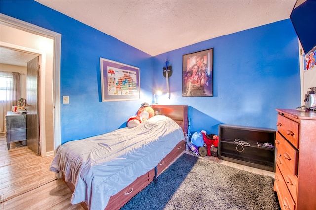 bedroom featuring a textured ceiling and light hardwood / wood-style flooring