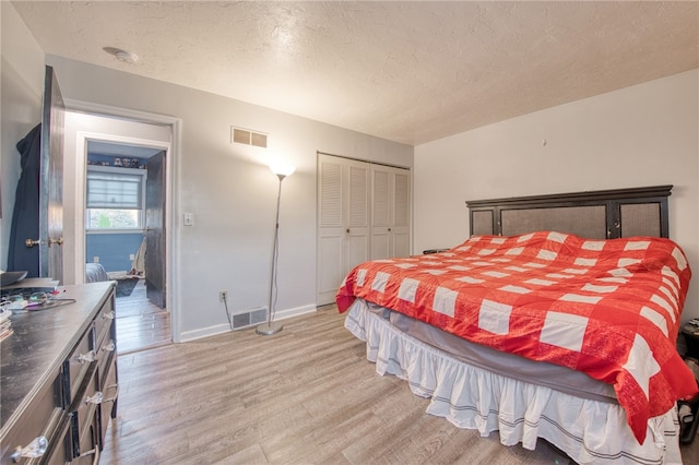 bedroom with light hardwood / wood-style floors, a textured ceiling, and a closet