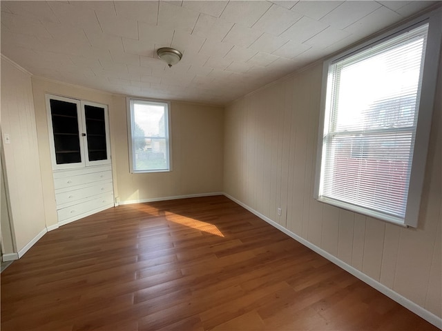 empty room with hardwood / wood-style floors, a wealth of natural light, and wood walls