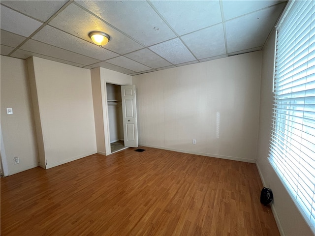 unfurnished bedroom featuring hardwood / wood-style floors, a paneled ceiling, and a closet