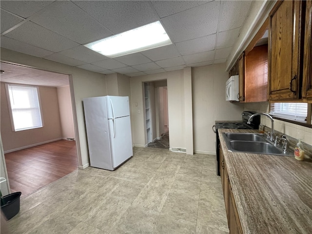 kitchen featuring a paneled ceiling, white appliances, sink, and light hardwood / wood-style floors