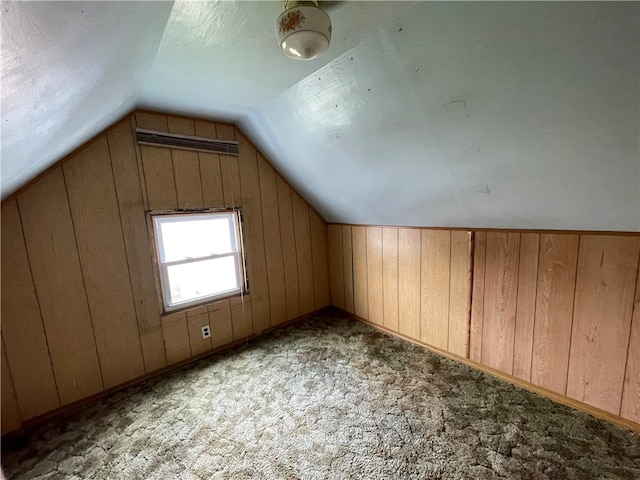 bonus room with wooden walls, vaulted ceiling, and dark colored carpet