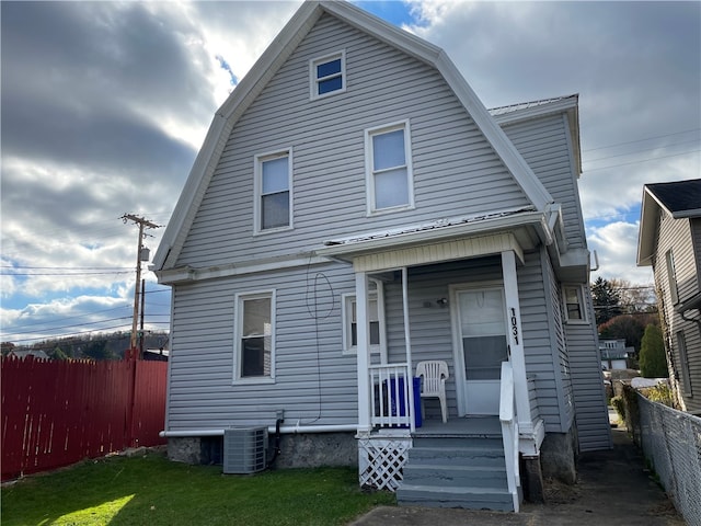 view of front of home with a front yard, covered porch, and central AC