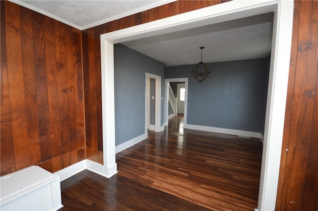 interior space with wood walls, dark hardwood / wood-style floors, an inviting chandelier, and ornamental molding