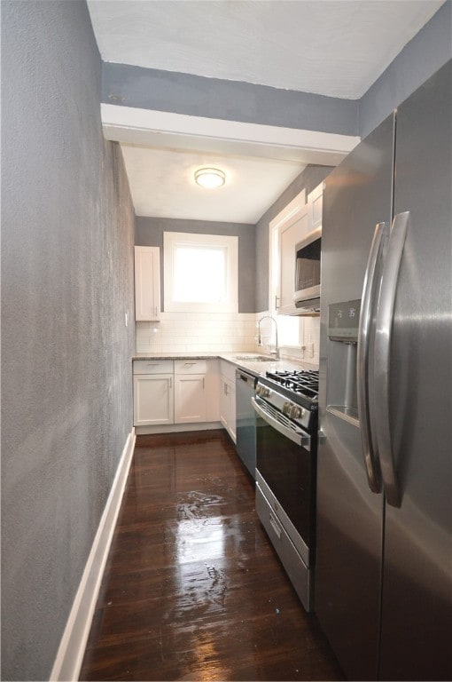 kitchen with tasteful backsplash, appliances with stainless steel finishes, dark hardwood / wood-style floors, sink, and white cabinets