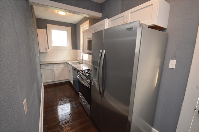 kitchen featuring white cabinetry, sink, appliances with stainless steel finishes, dark hardwood / wood-style floors, and backsplash