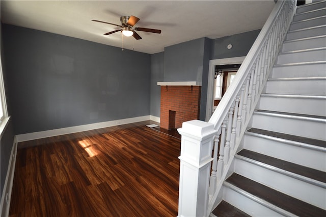 staircase featuring hardwood / wood-style floors, ceiling fan, and a fireplace