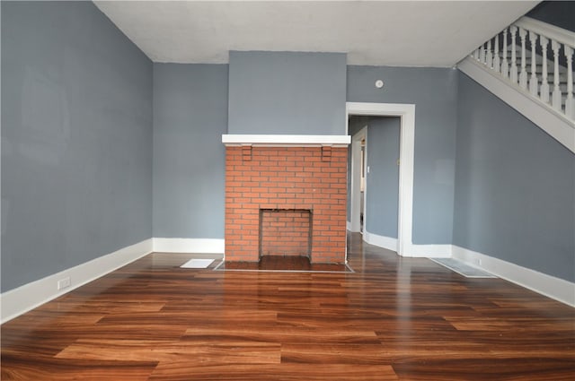 unfurnished living room with a brick fireplace and hardwood / wood-style flooring