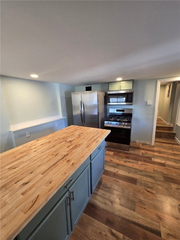 kitchen with dark wood-type flooring, butcher block countertops, and stainless steel appliances