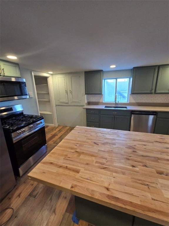 kitchen featuring stainless steel appliances, wood-type flooring, sink, and butcher block counters