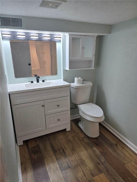 bathroom with hardwood / wood-style flooring, vanity, toilet, and a textured ceiling