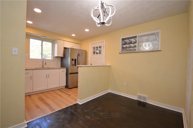 kitchen with white cabinets, sink, stainless steel fridge with ice dispenser, light hardwood / wood-style flooring, and decorative light fixtures