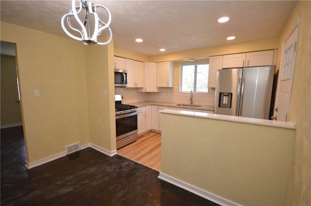 kitchen with hanging light fixtures, wood-type flooring, white cabinetry, and appliances with stainless steel finishes