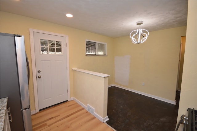 doorway to outside featuring an inviting chandelier and light hardwood / wood-style flooring