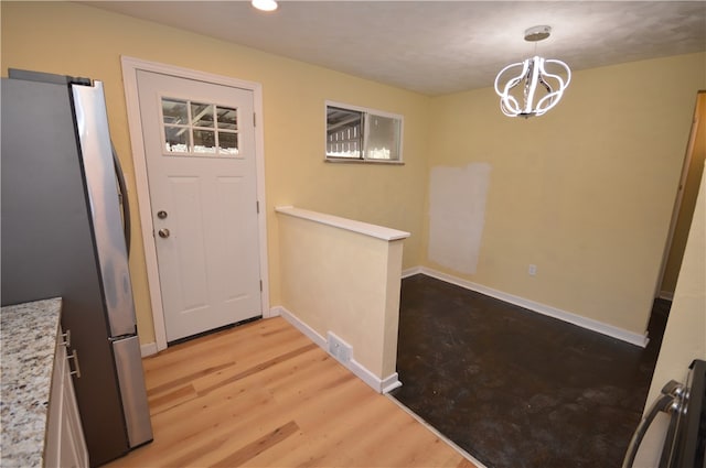 doorway featuring light wood-type flooring and a notable chandelier