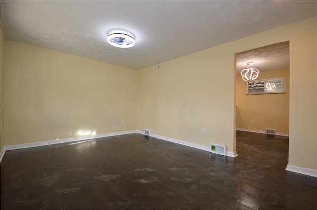 empty room with dark hardwood / wood-style floors and a chandelier