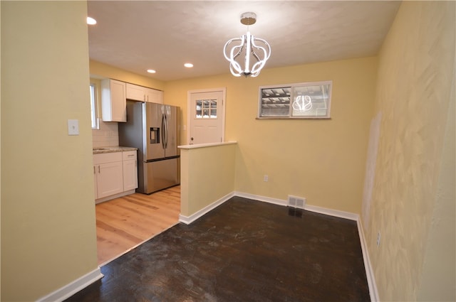 kitchen with backsplash, decorative light fixtures, stainless steel refrigerator with ice dispenser, hardwood / wood-style flooring, and white cabinets