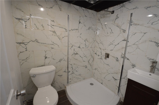 bathroom with tile walls, tiled shower, vanity, and toilet