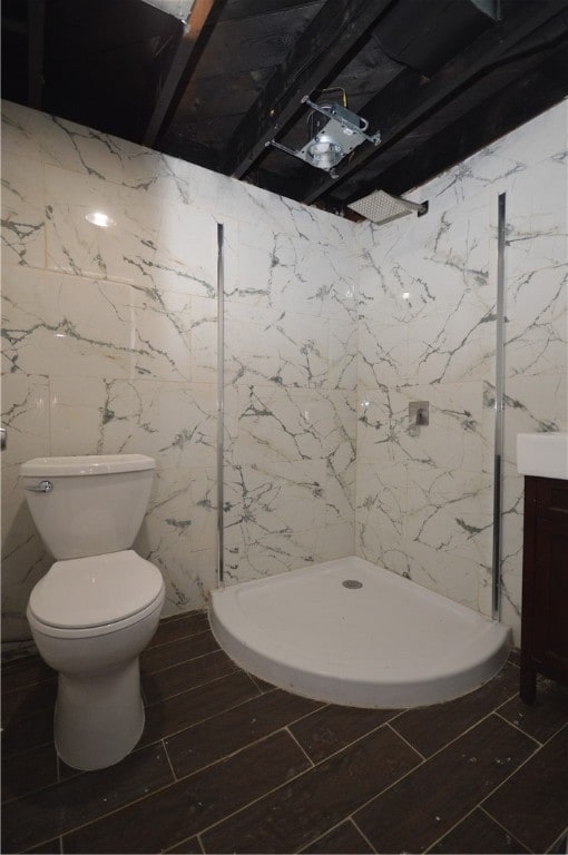 bathroom featuring a shower, vanity, toilet, and tile walls