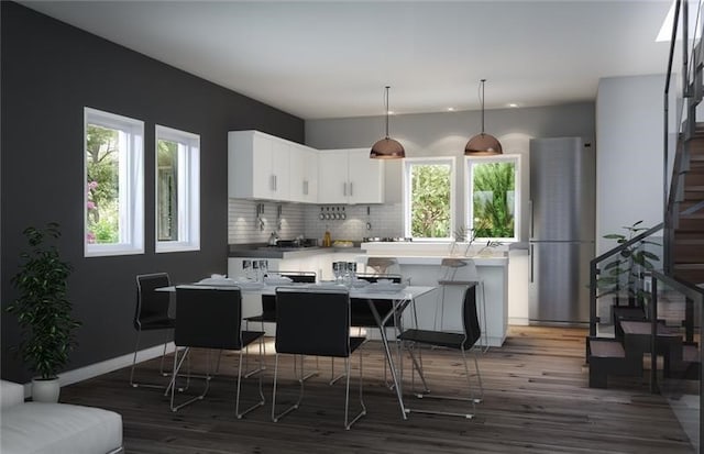 kitchen featuring white cabinets, a healthy amount of sunlight, a kitchen island, and stainless steel fridge