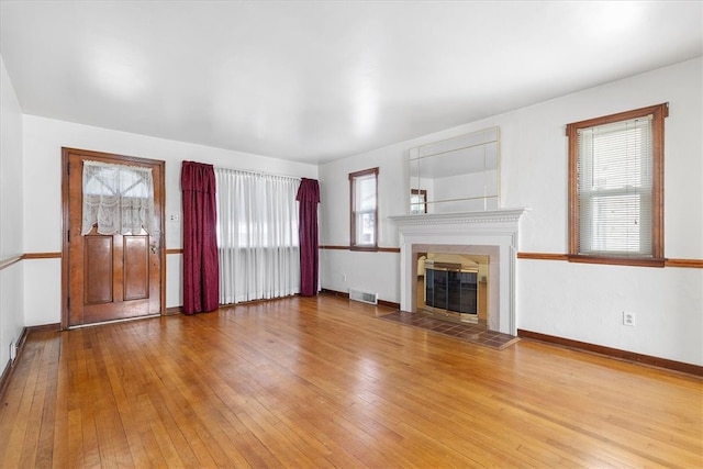 unfurnished living room with light hardwood / wood-style flooring and a tile fireplace