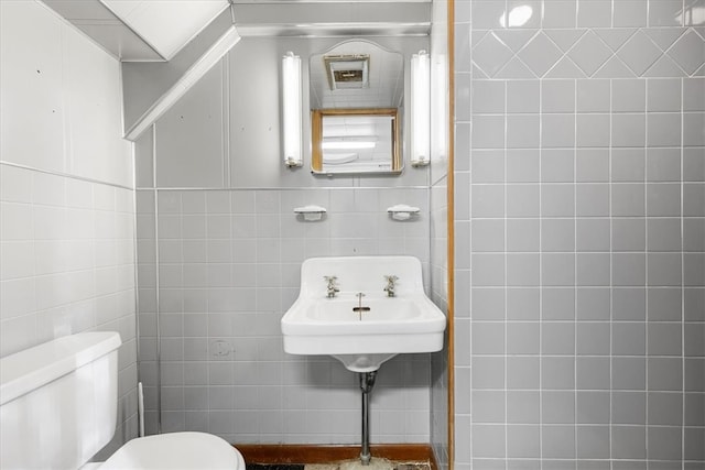 bathroom featuring tile walls and toilet