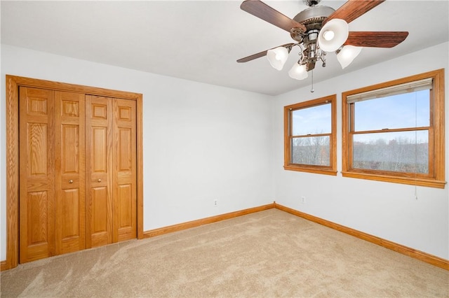 unfurnished bedroom featuring ceiling fan, light colored carpet, and a closet