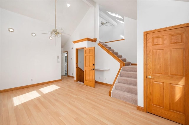 unfurnished living room with ceiling fan, beamed ceiling, light hardwood / wood-style flooring, and high vaulted ceiling