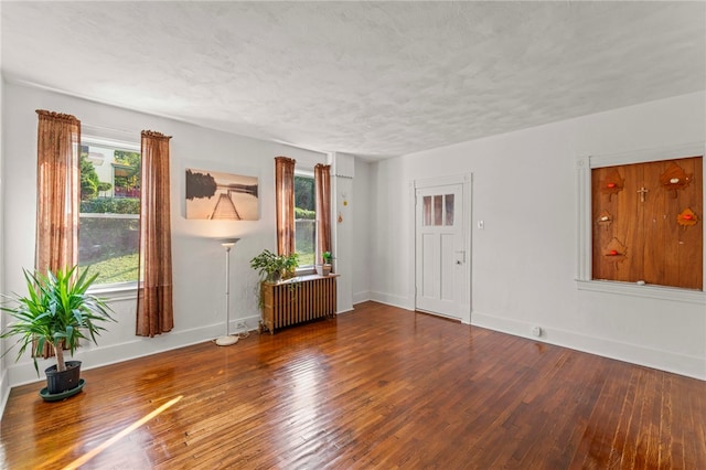 empty room with wood-type flooring, a textured ceiling, and radiator