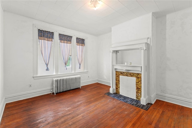 unfurnished living room featuring radiator heating unit and dark wood-type flooring