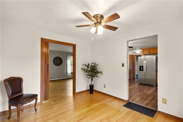 spare room with a baseboard heating unit, ceiling fan, and light hardwood / wood-style flooring