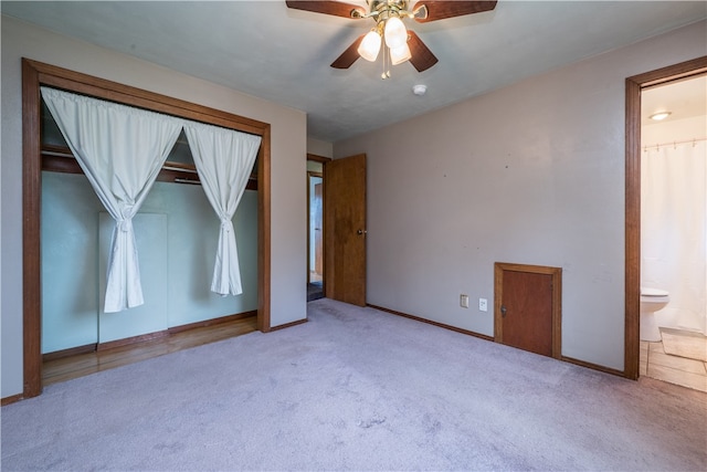 unfurnished bedroom featuring ensuite bathroom, light carpet, ceiling fan, and a closet