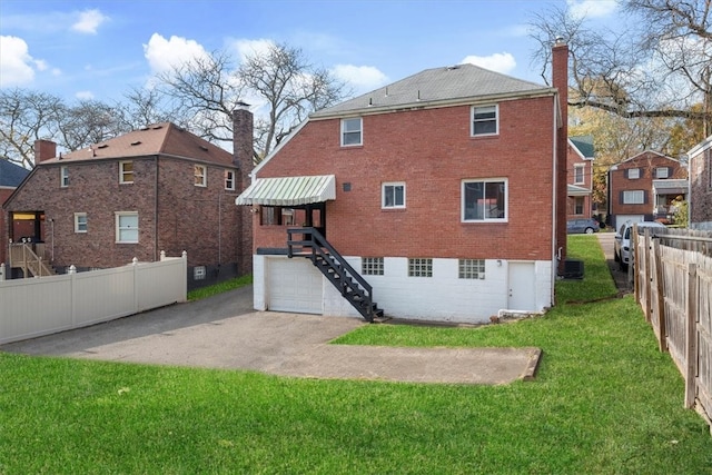 rear view of house with central AC and a yard