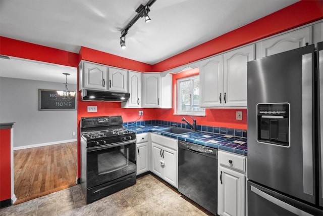 kitchen featuring black appliances, white cabinetry, tile counters, and track lighting