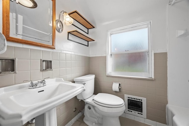 bathroom with sink, heating unit, a washtub, toilet, and tile walls