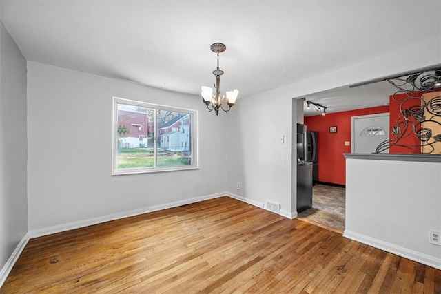 unfurnished dining area featuring hardwood / wood-style flooring and an inviting chandelier