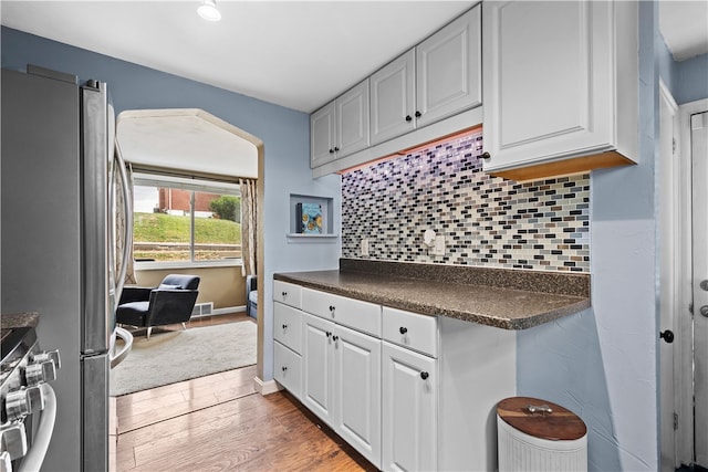 kitchen featuring backsplash, appliances with stainless steel finishes, light hardwood / wood-style floors, and white cabinets